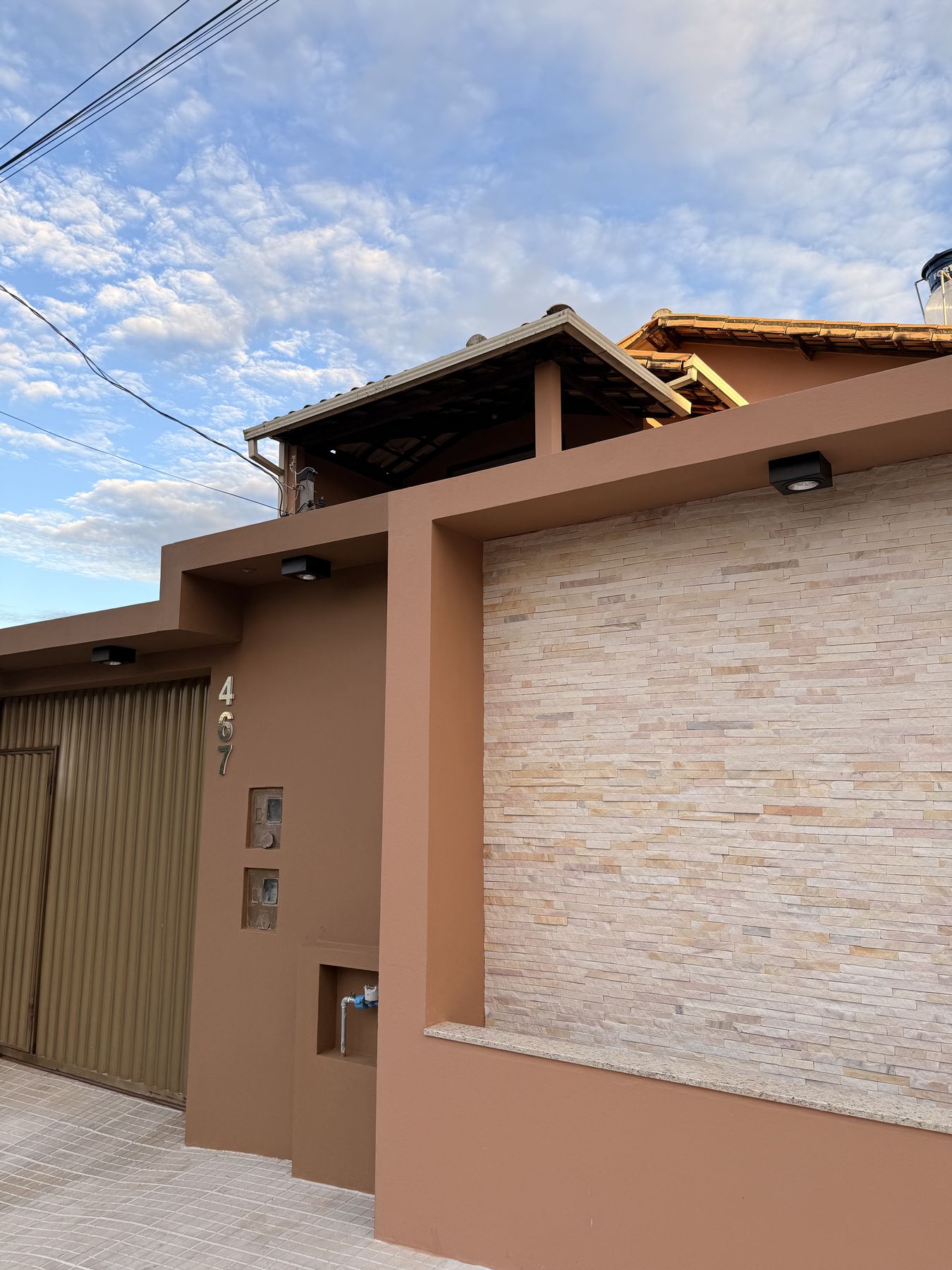 Fachada de residência em Entre Rios de Minas com revestimento em pedra e portão em madeira